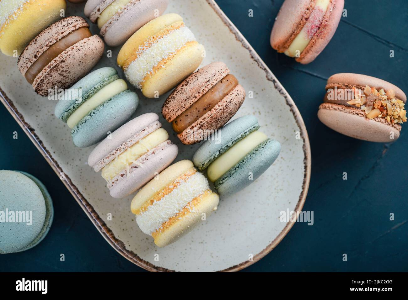Bunte französische Macarons auf Teller auf schwarzem Hintergrund Stockfoto