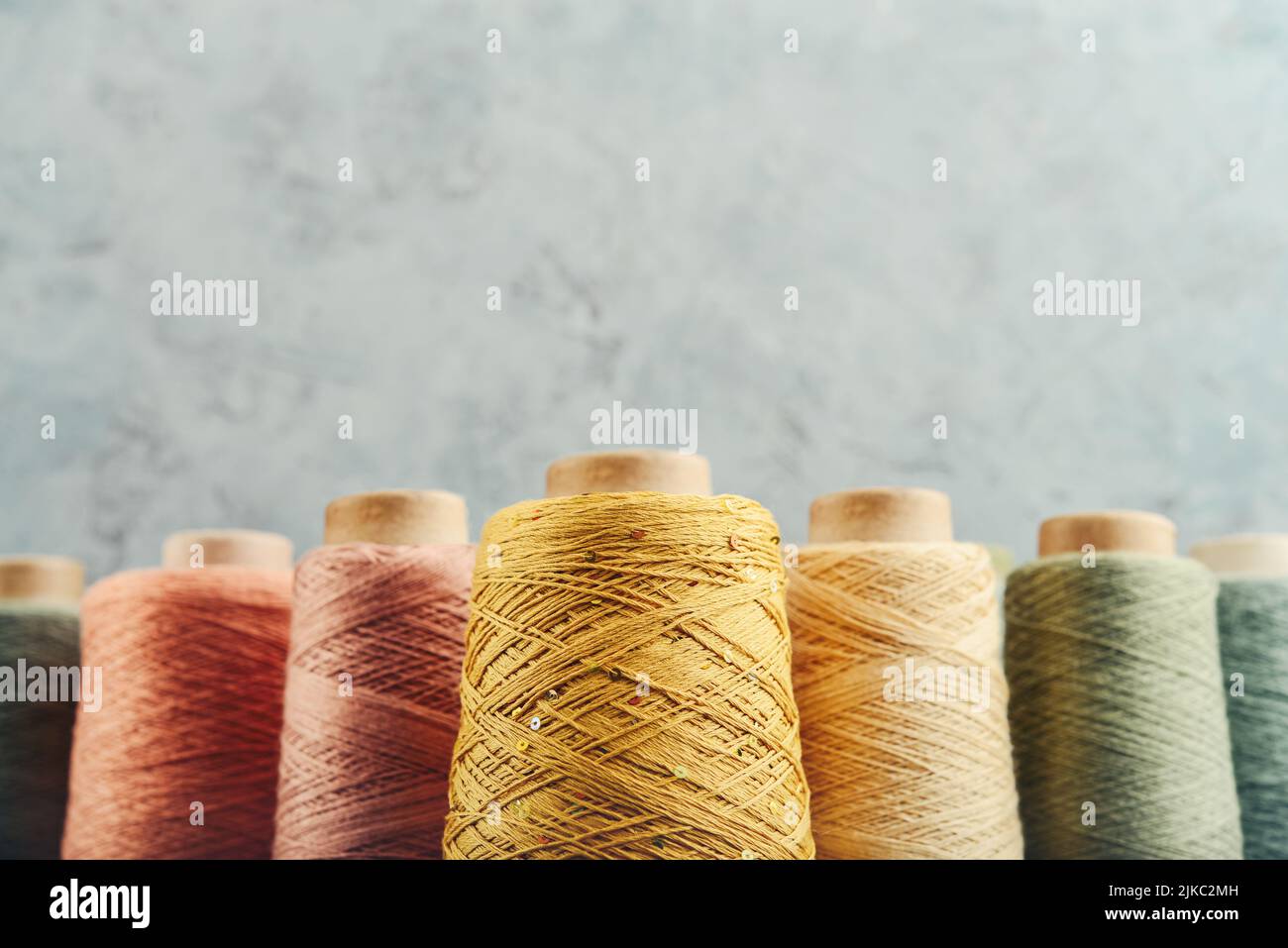 Set aus farbigem Garn zum Stricken auf Kegel auf hellem Hintergrund, mit Kopierraum Stockfoto