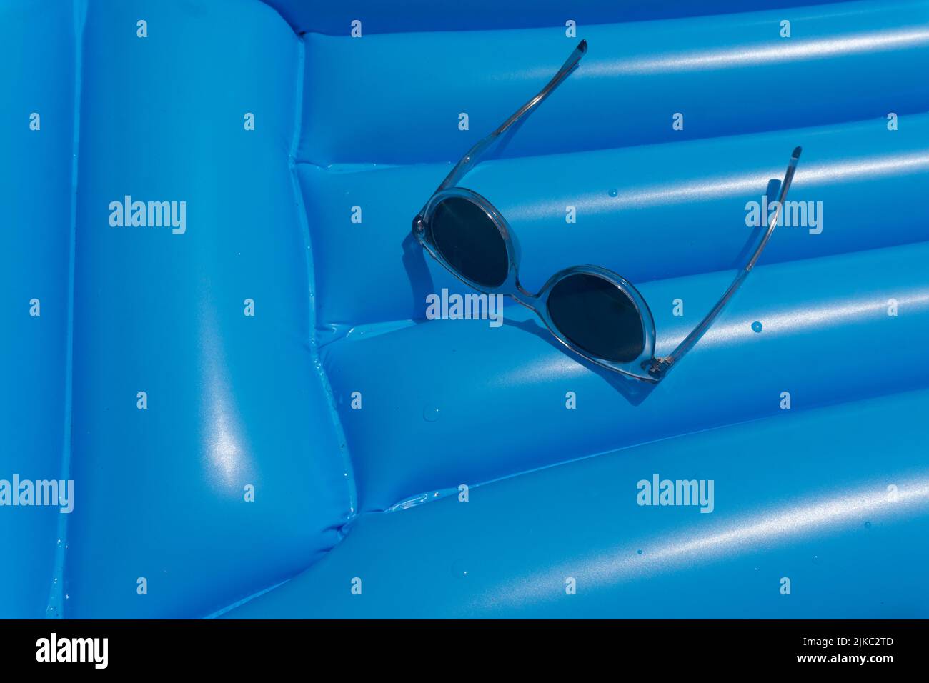 Sonnenbrillen auf einem blauen Schwimm-Schwimmer. Sommerferien Hintergrund Stockfoto