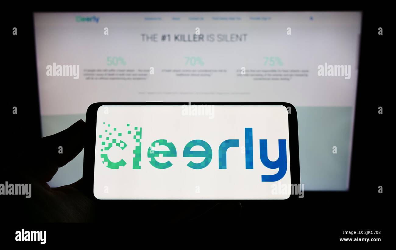 Person, die das Smartphone mit dem Logo des US-Gesundheitsunternehmens Cleerly Inc. Auf dem Bildschirm vor der Website hält. Konzentrieren Sie sich auf die Telefonanzeige. Stockfoto