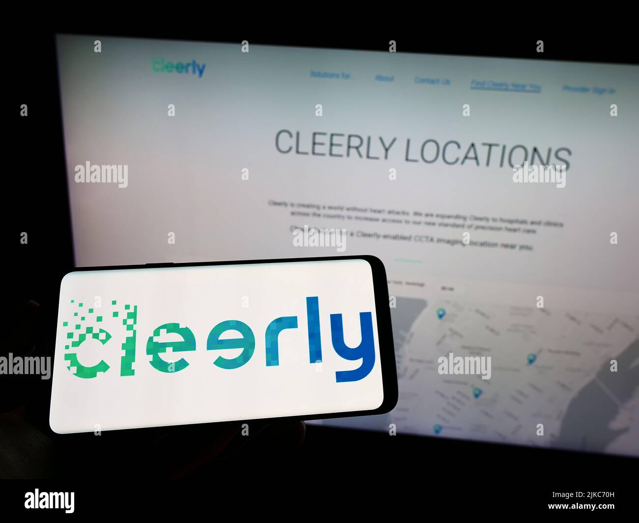 Person, die ein Mobiltelefon mit dem Logo des amerikanischen Gesundheitsunternehmens Cleerly Inc. Auf dem Bildschirm vor der Business-Webseite hält. Konzentrieren Sie sich auf die Telefonanzeige. Stockfoto