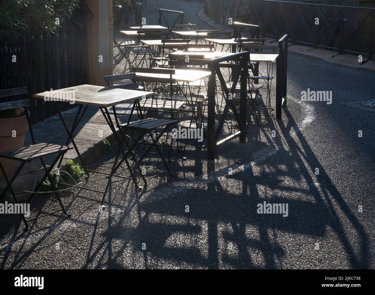 Arles, Frankreich. Leere Kaffeetische mit Schatten, in der Hitze des Tages. Stockfoto