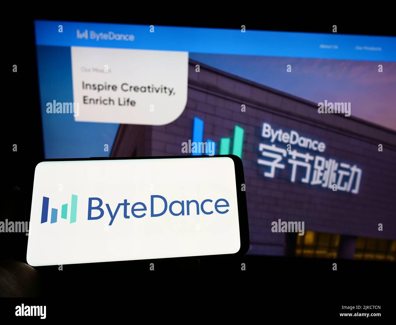Person mit Mobiltelefon und Logo des chinesischen Technologieunternehmens Bytedance Ltd. Auf dem Bildschirm vor der Business-Webseite. Konzentrieren Sie sich auf die Telefonanzeige. Stockfoto