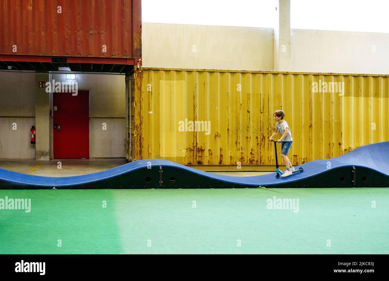 Junge, der einen Roller in der Halle fährt Stockfoto