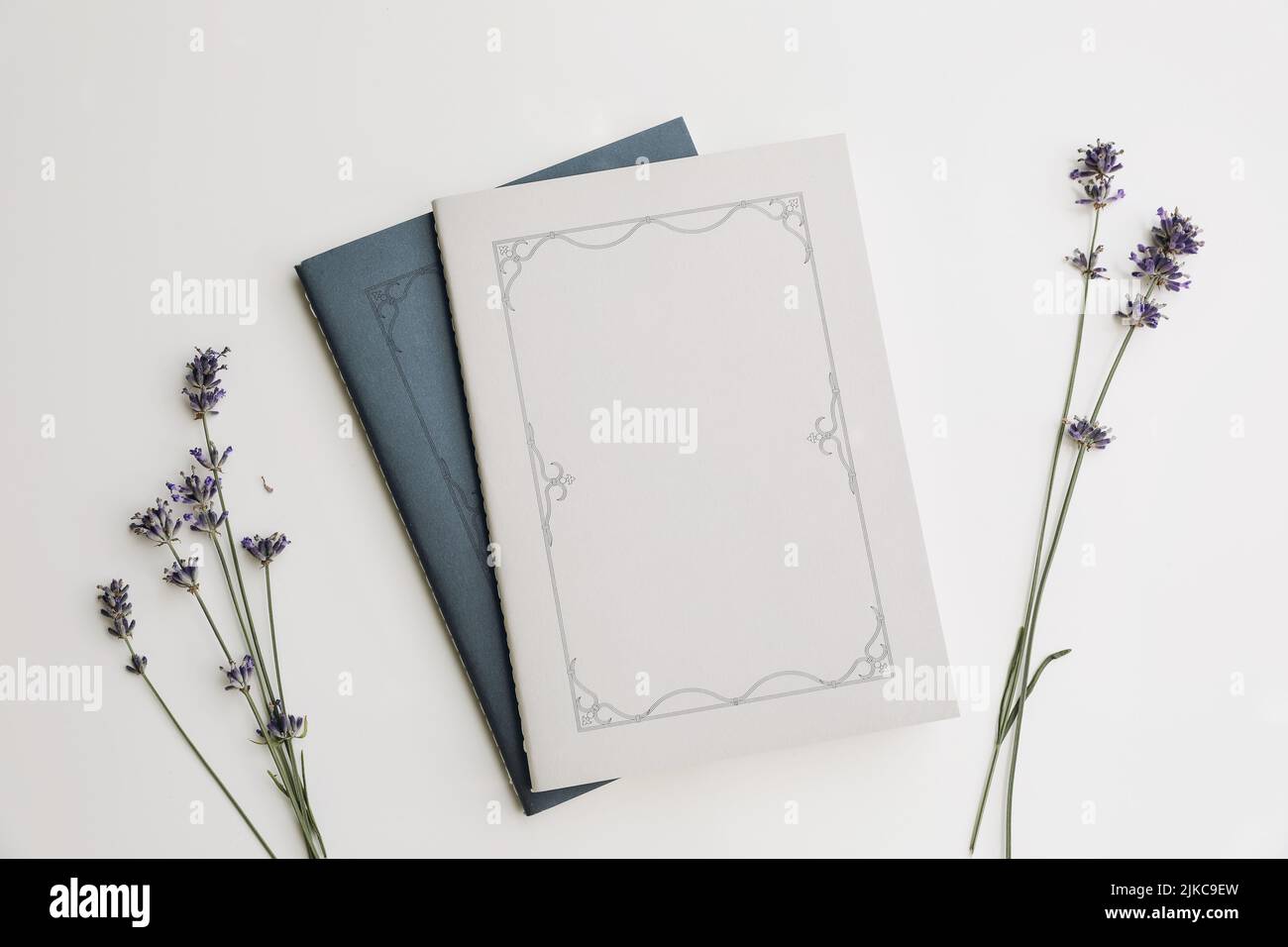 Sommer Lifestyle florale Komposition. Blau und grau Tagebuch Cover, Buch Mockups Szene mit Lavendelblüten im Sonnenlicht. Beige Tisch Hintergrund. Flach liegend Stockfoto