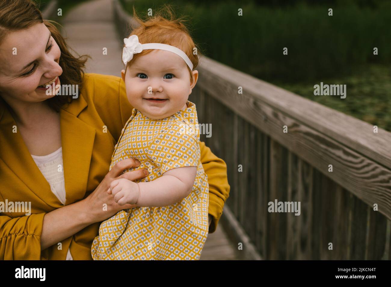 Mutter hält und lächelt über glückliche Rotkopftochter Stockfoto