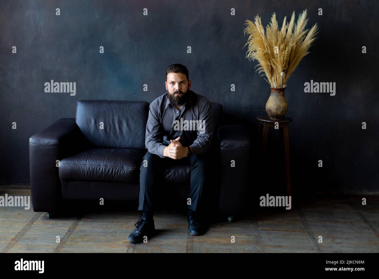 Ein Mann mit schwarzem Bart sitzt auf einem Ledersofa. Geschäftsmann Stockfoto