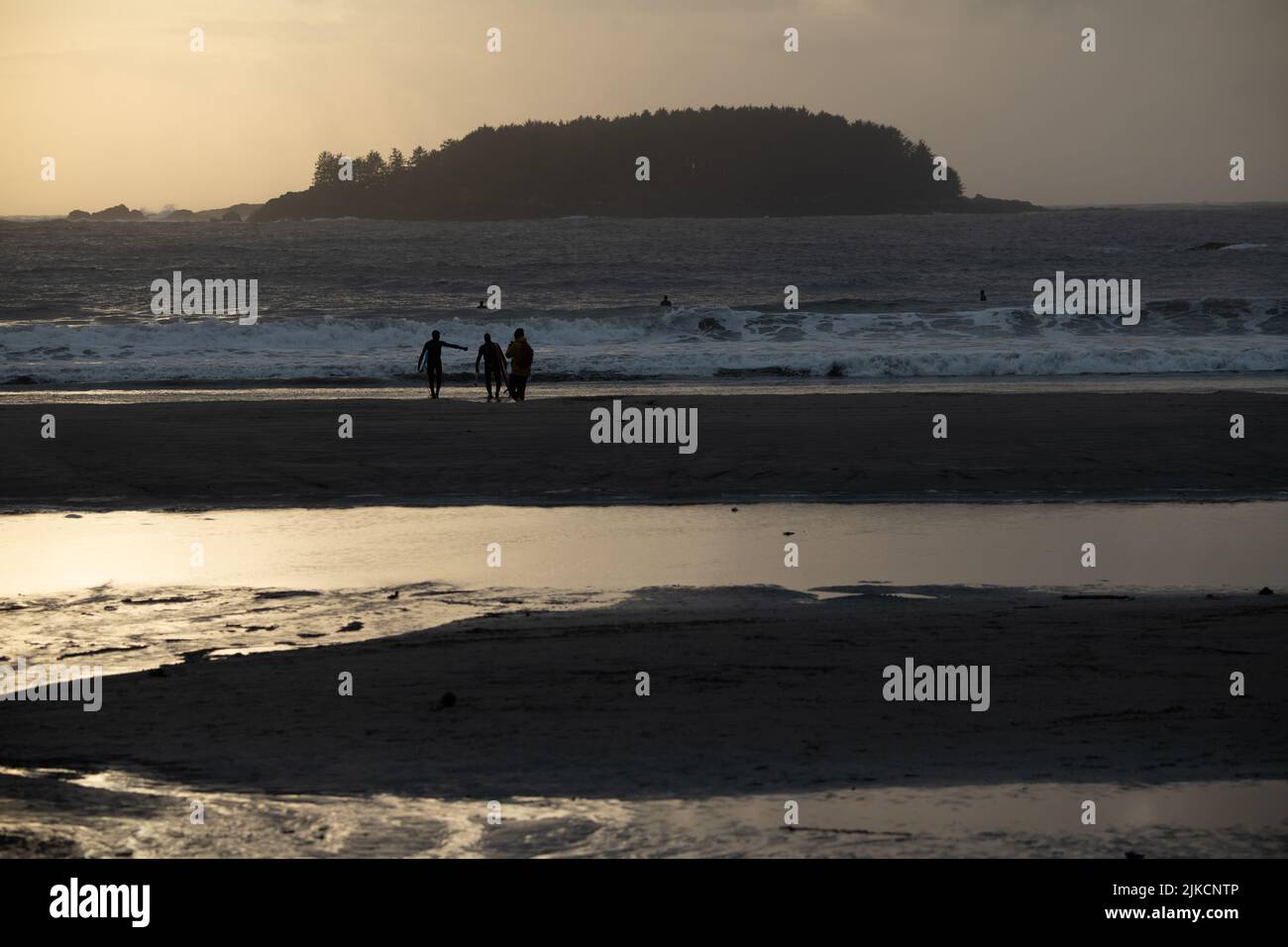 Surfer schlendern am Strand bei Sonnenuntergang in Tofino BC Stockfoto