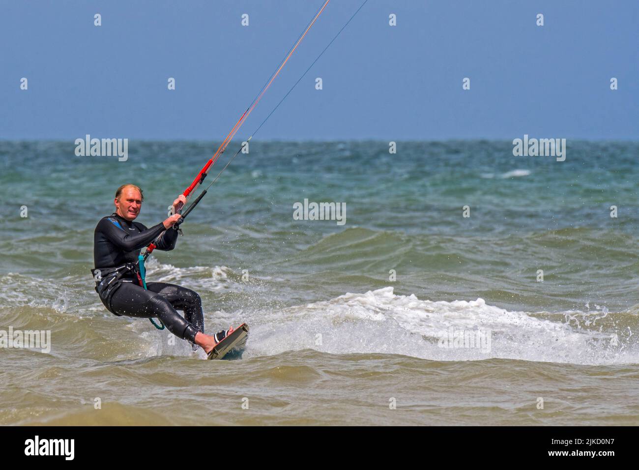 Kiteboarder / Kitesurfer trägt Neoprenanzug auf dem Twintip Board Kitesurfing an der Nordsee Stockfoto