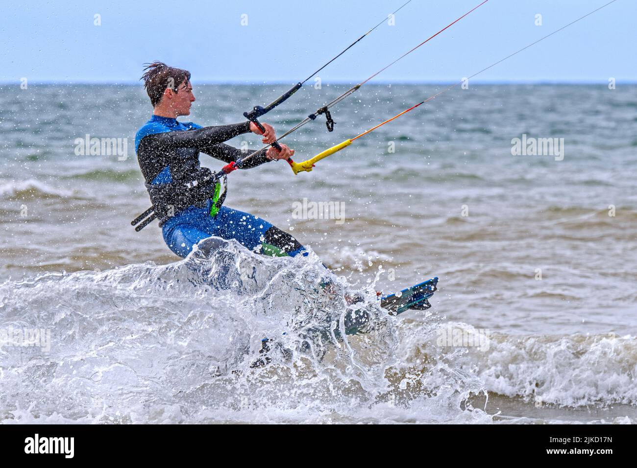 Junger Kiteboarder / Kitesurfer trägt Neoprenanzug auf dem Twintip Board Kitesurfing an der Nordsee Stockfoto