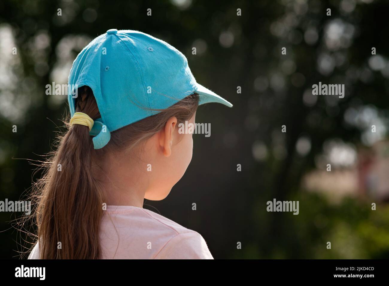 Kind im Grundschulalter, Mädchen, das etwas ansieht, von hinten gesehen, Platz kopieren, Rückseite des Kopfes Nahaufnahme Baseballmütze verschwommener Hintergrund, ein pe Stockfoto