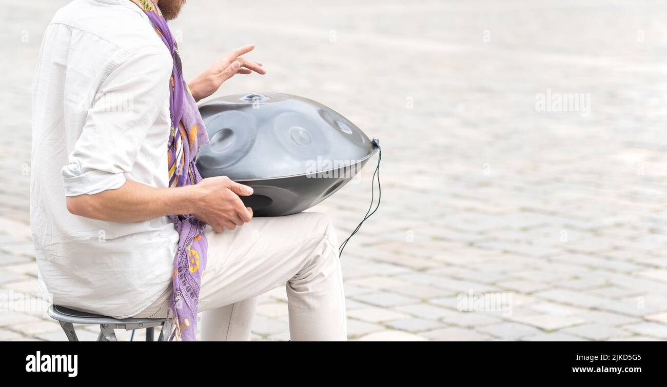 Mann, der die Hangtrommel spielt, Handpfanne, Stahlpfanne im Freien, Nahaufnahme der Hände, Zeitlupe. Musik, ungewöhnliche Perkussionsinstrumente, Entspannungsconce Stockfoto
