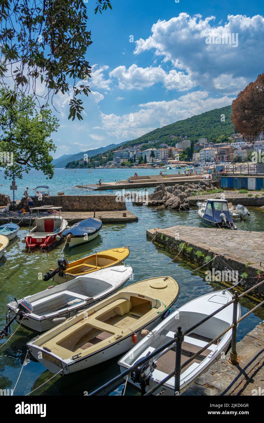 Blick auf felsigen Einlass und Boote mit Stadt Opatija im Hintergrund, Opatija, Kvarner Bucht, Kroatien, Europa Stockfoto