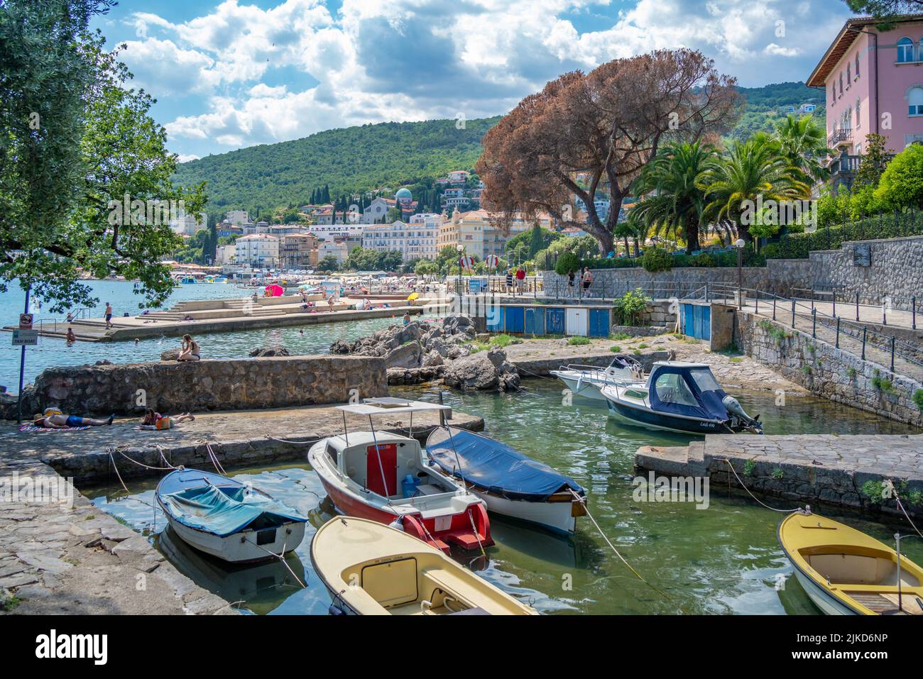 Blick auf felsigen Einlass und Boote mit Stadt Opatija im Hintergrund, Opatija, Kvarner Bucht, Kroatien, Europa Stockfoto