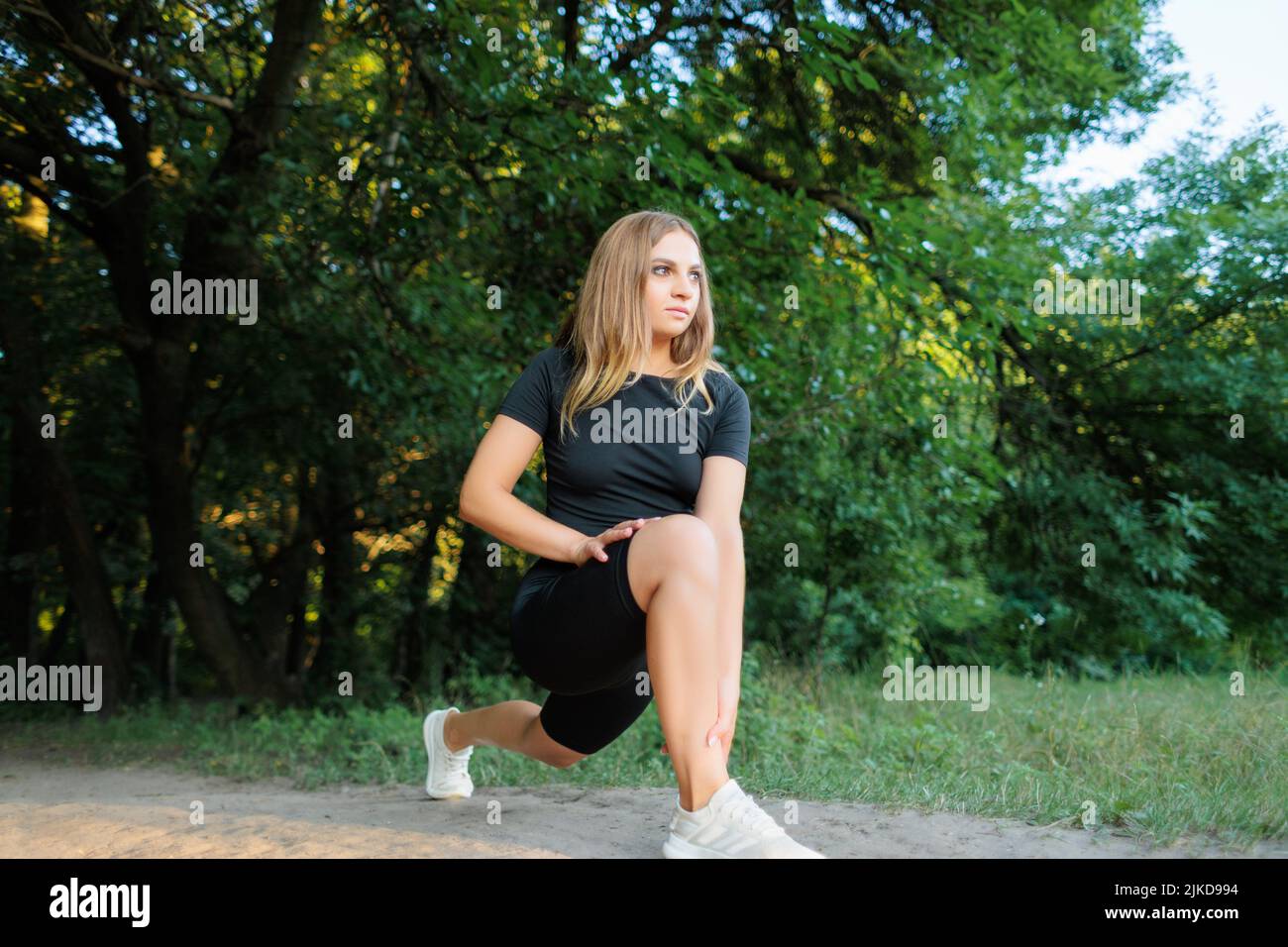 Blonde Sportmädchen führt Elemente zum Strecken der Beine, Kippen, auf dem Bein lehnen und Durchführen von Stretching Stockfoto