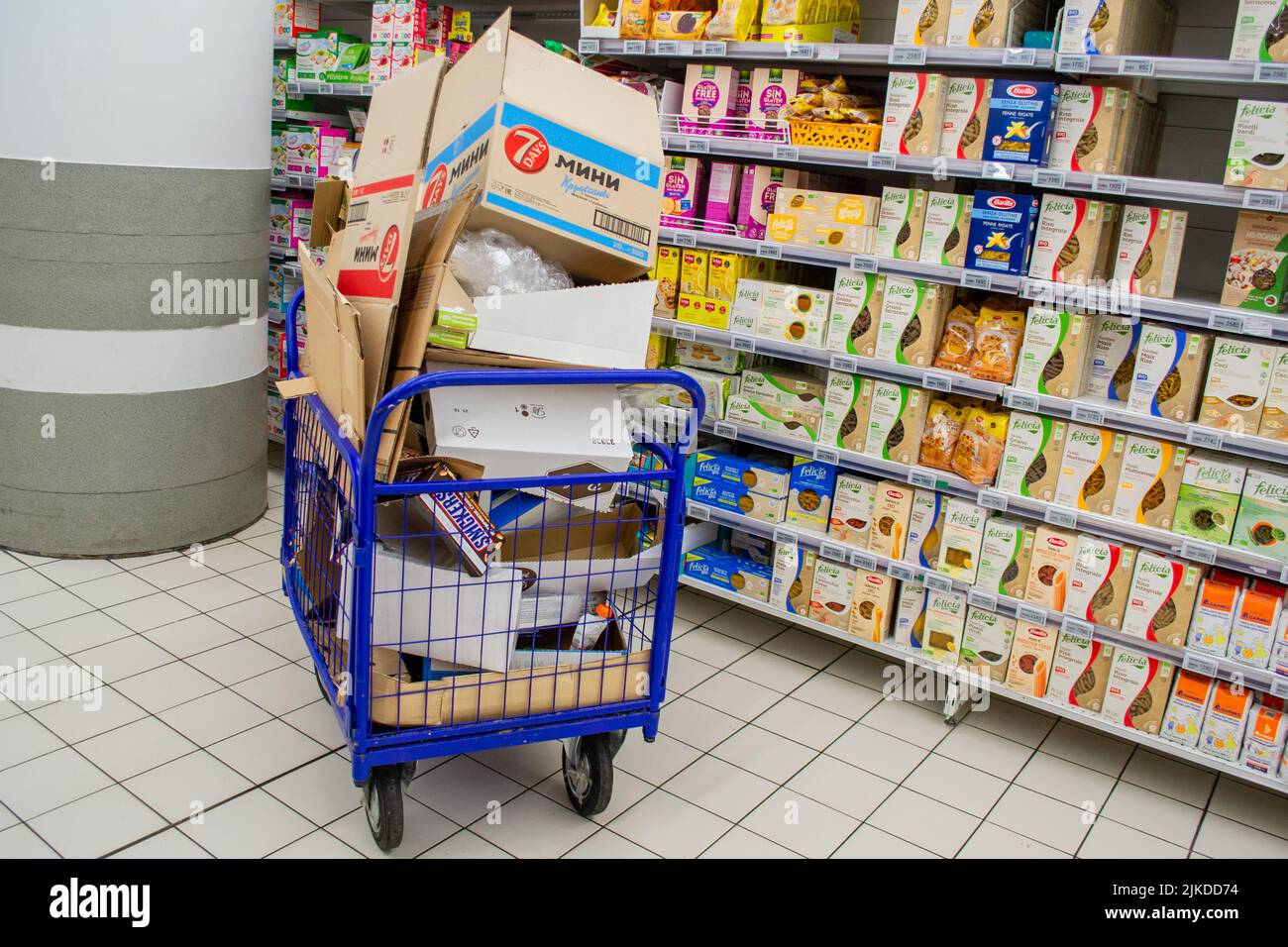 Moskau, Russland, September 2019: Ein riesiger Güterwagen mit einem Haufen leerer Kartons mit Waren in einem Supermarkt auf dem Hintergrund einer Reihe mit Prod Stockfoto