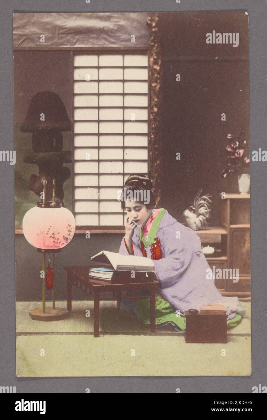 Junge Frau liest in der Nähe der Lampe. Pacific Pursuits : Postkarten Japan - Leben. Ausstellungsdatum: 1900 - 1940 Ausstellungsdatum: 1907 - 1918 Ort: s.l. Herausgeber: Stockfoto