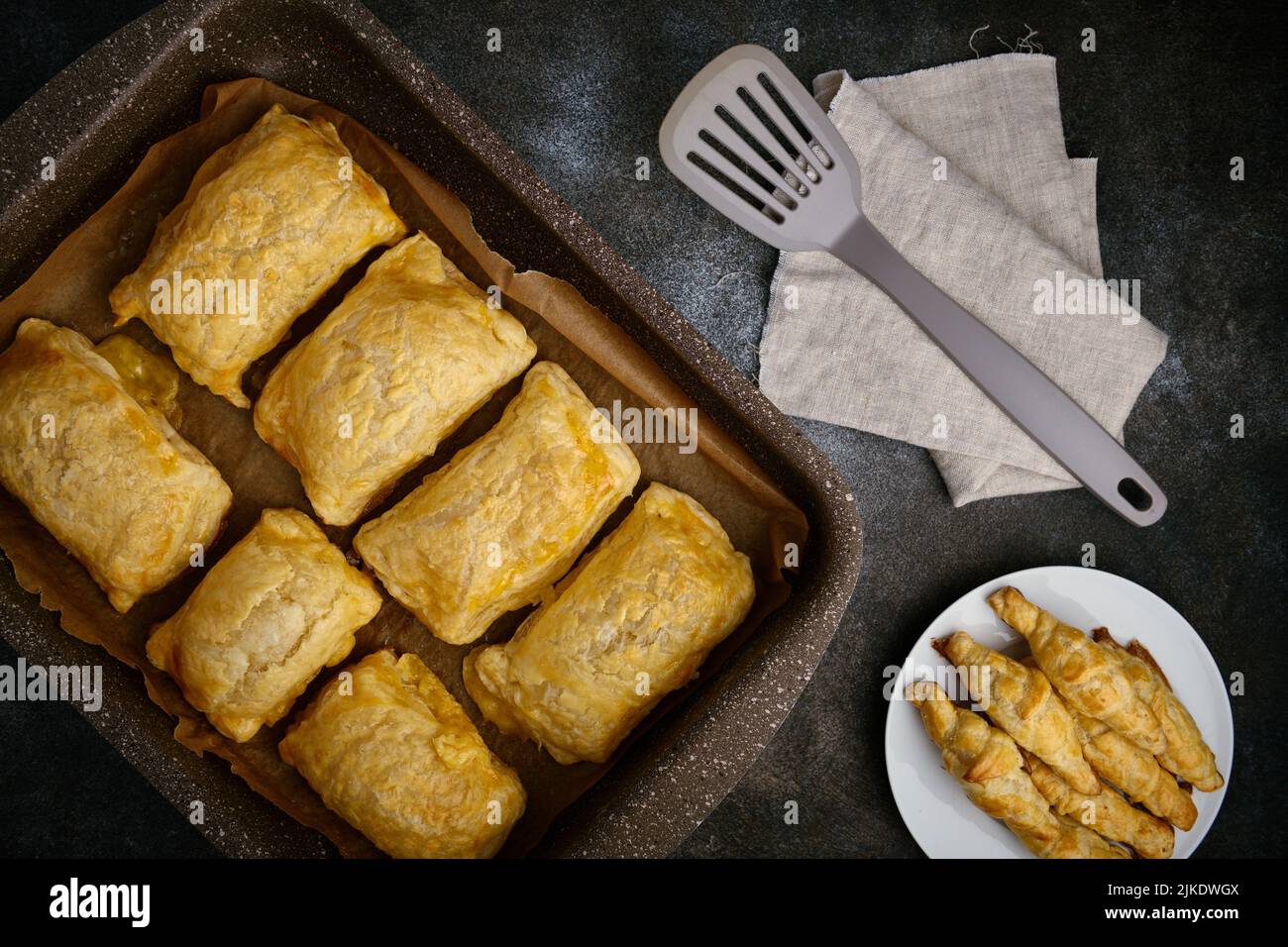 Heißer Blätterteig und Käsepatties liegen in einem antihaftbeschichteten Backblech, flach liegend Stockfoto