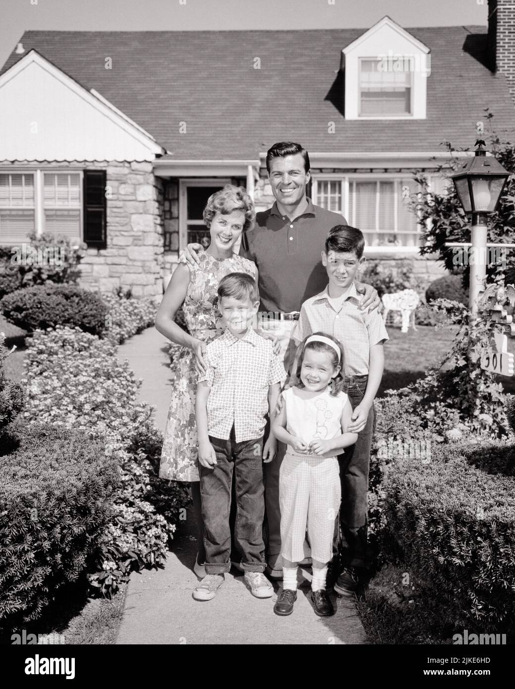 1960S PORTRÄT EINER LÄCHELNDEN FÜNFKÖPFIGEN FAMILIE, DIE VOR IHREM VORSTADTHAUS STEHT, MUTTER VATER MIT ZWEI JUNGEN UND EIN MÄDCHEN - J11124 HAR001 HARS MÜTTER ALTE ZEIT ZUKUNFT NOSTALGIE BRUDER ALTE MODE SCHWESTER 1 JUGENDLICHE GLEICHGEWICHT STARKE SÖHNE ZUFRIEDEN FAMILIEN FREUDE LIFESTYLE FÜNF FEIER FRAUEN HÄUSER VERHEIRATET 5 BRÜDER EHEGATTEN EHEMÄNNER ZU HAUSE LEBEN KOPIEREN RAUM IN VOLLER LÄNGE DAMEN TÖCHTER PERSONEN WOHNEN PFLEGE MÄNNER GEBÄUDE GESCHWISTER SPIRITUALITÄT VERTRAUEN SCHWESTERN VÄTER B&W PARTNER BLICKKONTAKT ERFOLG GLÜCK FRÖHLICHE STÄRKE VÄTER FORTSCHRITT STOLZ AUTORITÄT HÄUSER GESCHWISTER LÄCHELT VERBINDUNG Stockfoto