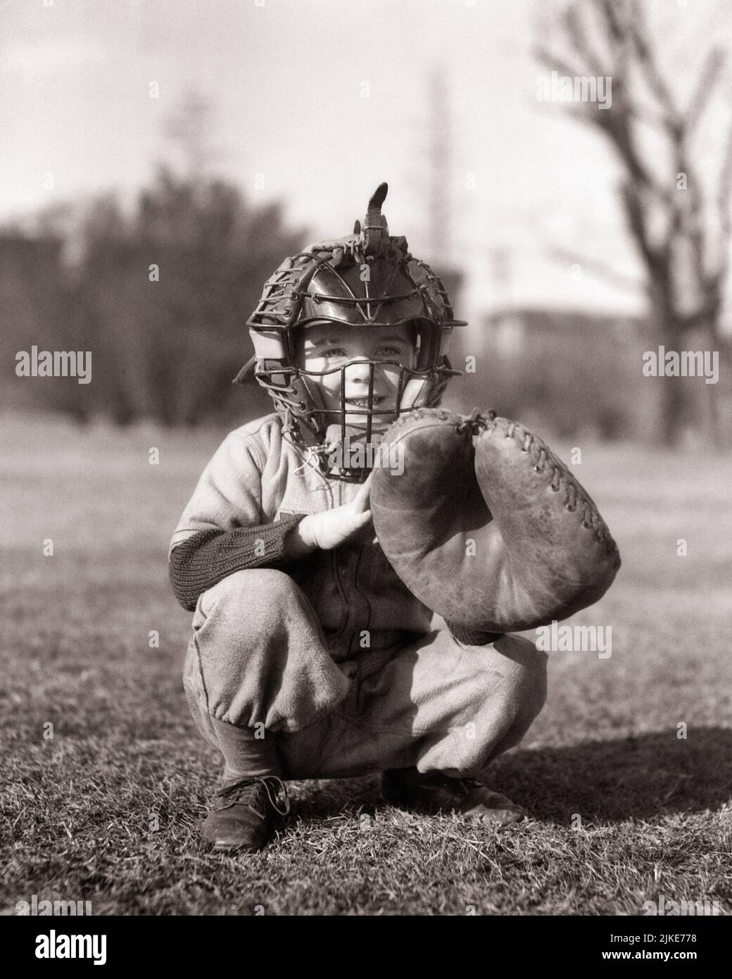 1930S KLEINER JUNGE TRÄGT BASEBALLUNIFORM IN TRADITIONELLER CATCHER’S-HALTUNG UND TRÄGT GESICHTSMASKENSCHUTZ UND CATCHER’S MITT - J1324 HAR001 HARS INSPIRATION TRADITIONELLE MÄNNER RISKIEREN VERTRAUEN B&W FANG GLÜCK FRÖHLICH LITTLE LEAGUE ABENTEUER FREIZEIT SCHUTZ STRATEGIE CATCHER MITT HOCKEN UND AUFREGUNG LOW ANGLE ERHOLUNG LÄCHELT KONZEPTIONELL FREUDIG UNTERSTÜTZUNG BALL SPIEL BALL SPORT ZUSAMMENARBEIT WACHSTUM JUGENDLICHE POSITION BASEBALLSCHLÄGER SCHWARZ UND WEISSE KAUKASISCHE ETHNIZITÄT HAR001 ALTMODISCHE HOCKENDE HALTUNG Stockfoto