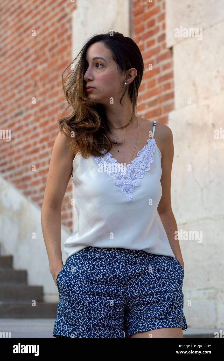 Junge Frau, die durch die Jardines de Sabatini in Madrid spazierengeht. Frau geht mit blauen Shorts und weißer Bluse Stockfoto