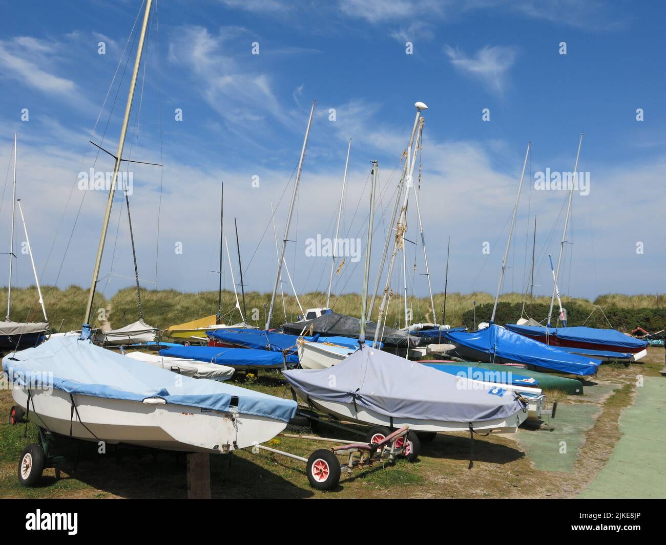 Boote, die an den Sanddünen am Strand von Findhorn an einem perfekten Sommertag mit nur wispigen Wolken in einem tiefblauen Himmel festgemacht sind. Stockfoto