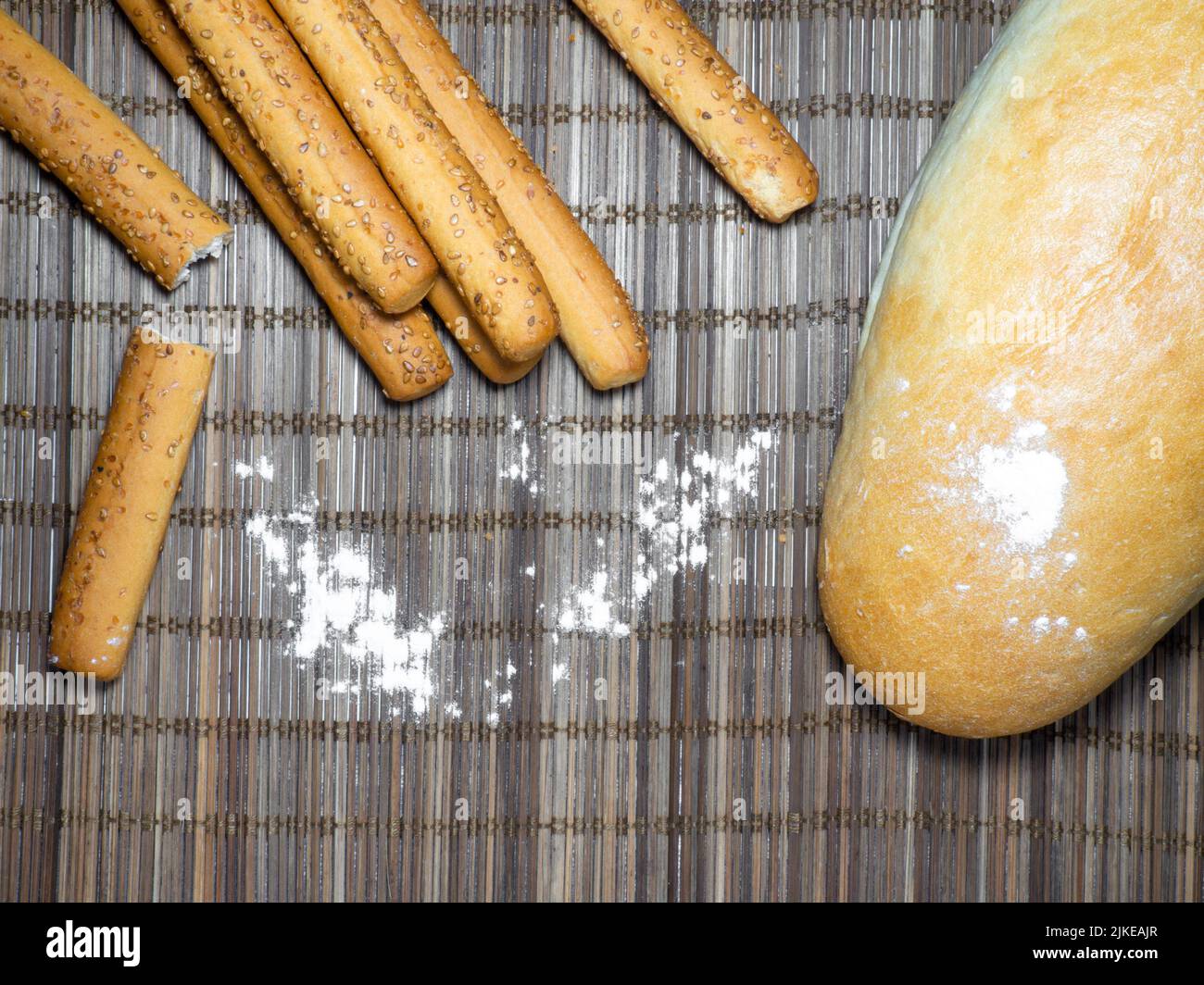 Sesamkekse und Brot auf dem Tisch. Kekse sind in Form von Stäben länglich. Brotprodukte. Mehlprodukte. Stockfoto