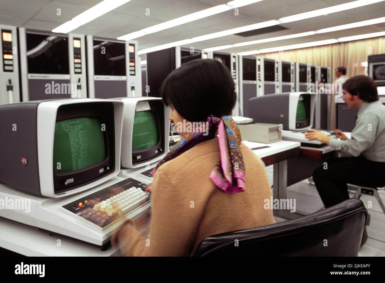 1970S JUNGE TECHNIKERIN, DIE VOR BURROUGHS COMPUTER MIT TASTATUR IM HINTERGRUND SITZT, SIND MAGNETBANDTRANSPORTE - KO687 HAR001 HARS LIFESTYLE FRAUEN JOBS KOPIEREN RAUM DAMEN COMPUTER PERSONEN TECHNIKER BERUF DATEN ZIELE WEITWINKEL GESCHICKLICHKEIT BERUF FÄHIGKEITEN MAINFRAME KOPF UND SCHULTERN KARRIERE SPANNUNG WISSEN KRAFTVOLLER FORTSCHRITT SIND INNOVATIONSARBEIT IN JOBS MIT CHANCEN, DIE VERBINDUNGSBEWEGUNGEN NUTZEN KONZEPTIONELLE STILVOLLE TRANSPORTE INFRASTRUKTUR MITARBEITER TERMINALS EINTRAG WACHSTUM PROGRAMMIERUNG TERMINAL JUNGE ERWACHSENE FRAU BURROUGHS KAUKASISCHEN ETHNIZITÄT COMPUTING Stockfoto