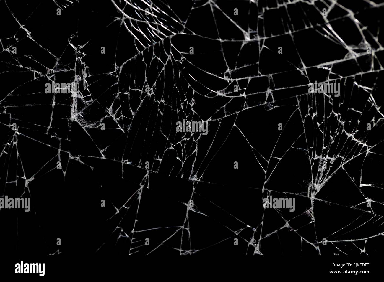 Altes schmutziges Glas mit vielen Rissen, altes zerbrochenes Glas auf schwarzem Hintergrund Stockfoto