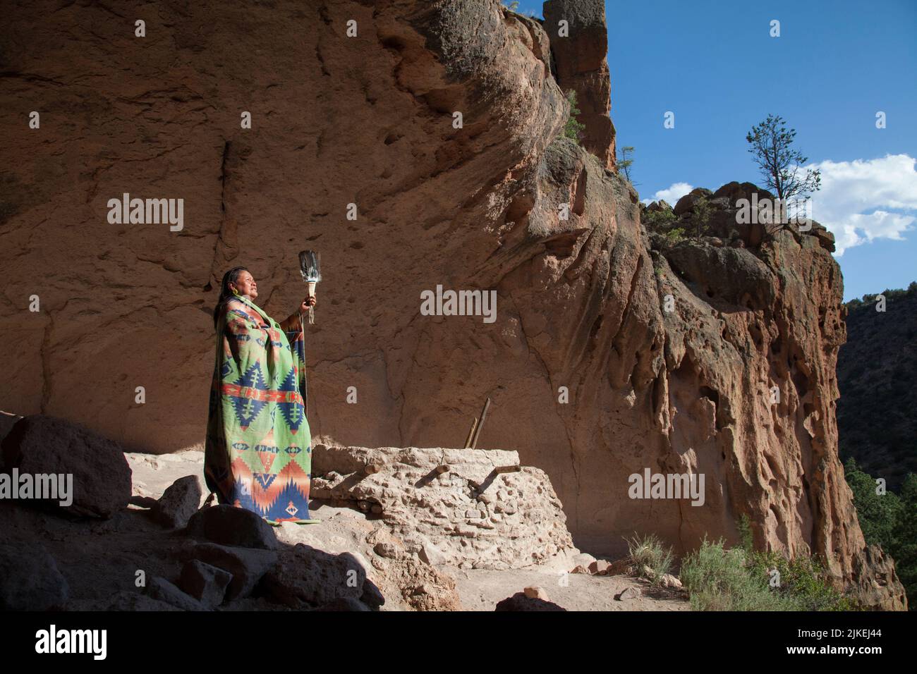 Die Frau trägt eine Decke der Ureinwohner Amerikas und segnet in einer heiligen Höhle mit Kiva, dem Bandolier National Monument, New Mexico Stockfoto