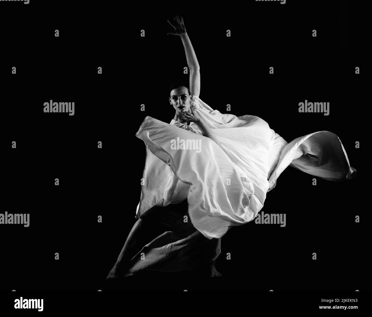 Eine Frau in einer weißen Robe auf schwarzem Hintergrund, eine Tänzerin, dramatischer Tanz Stockfoto