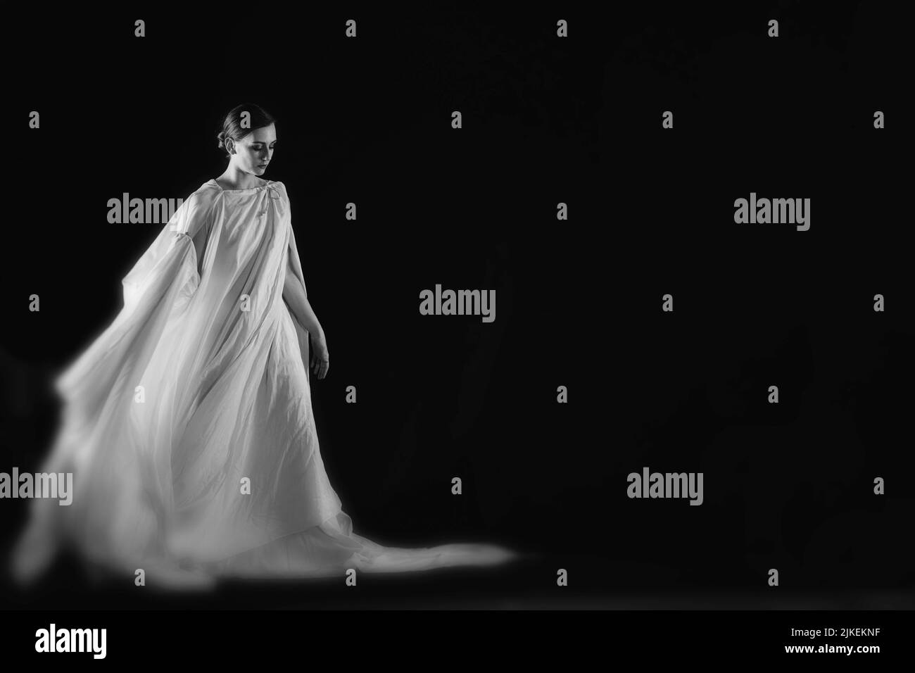 Eine Frau in einer weißen Robe auf schwarzem Hintergrund, eine Tänzerin, dramatischer Tanz Stockfoto