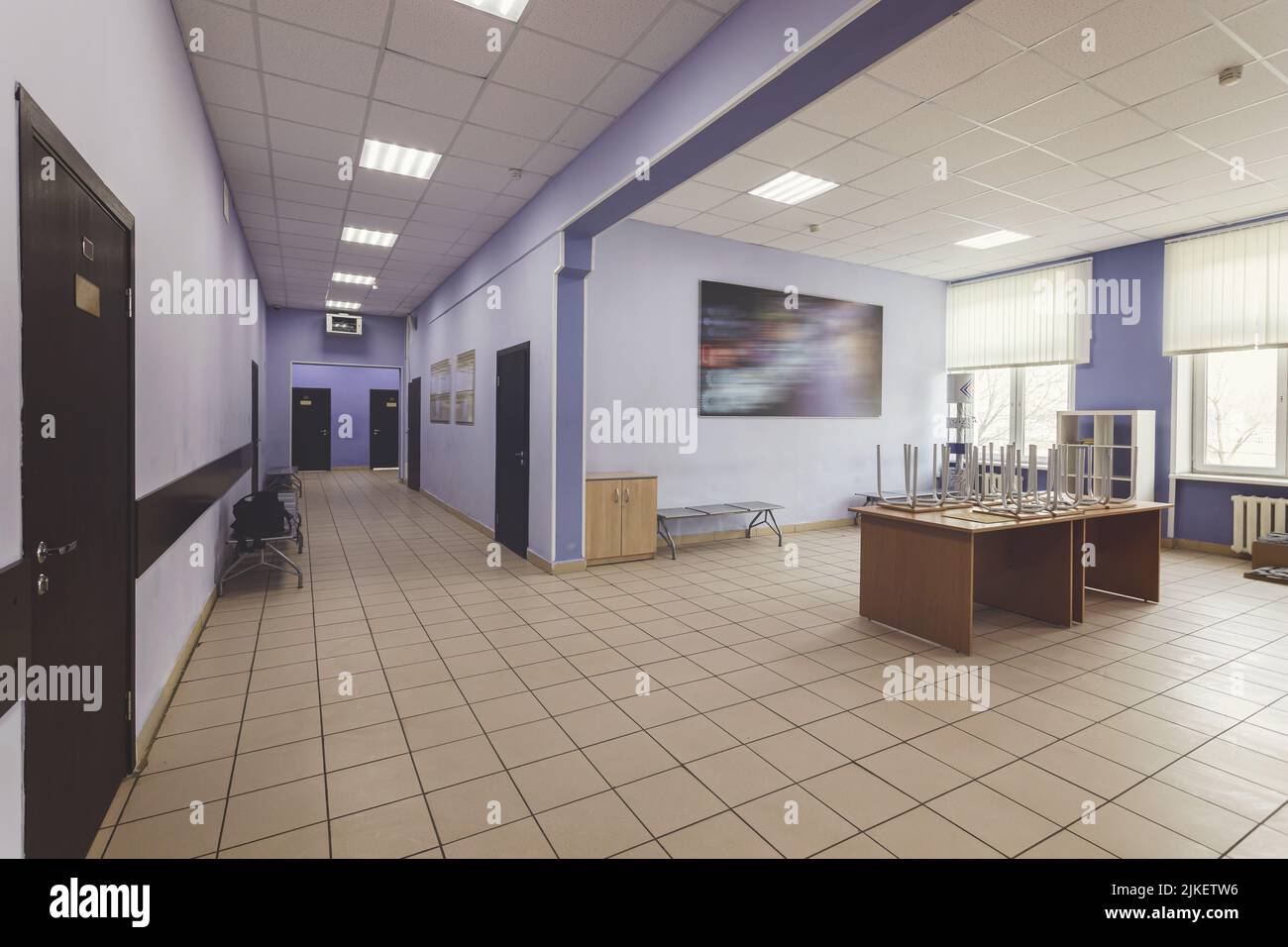 Schulflur, Flur der Hochschule oder Universität. Hellblaue Wände, braune Türen und gefliester Fußboden. Stockfoto