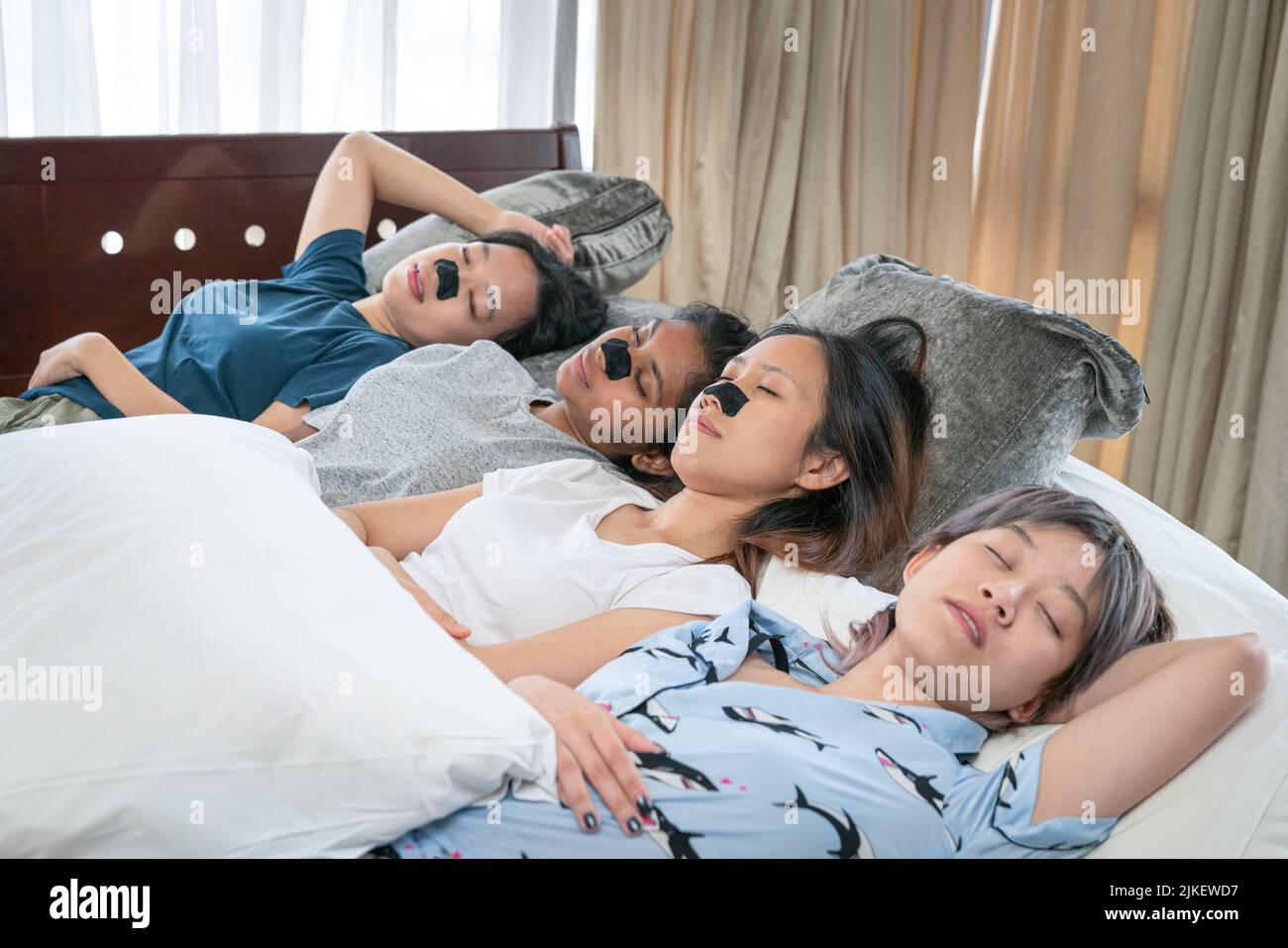 Junge Frauen aus verschiedenen Ethnien liegen schlafend auf dem Bett. Freundinnen Sleepover Konzept. Stockfoto