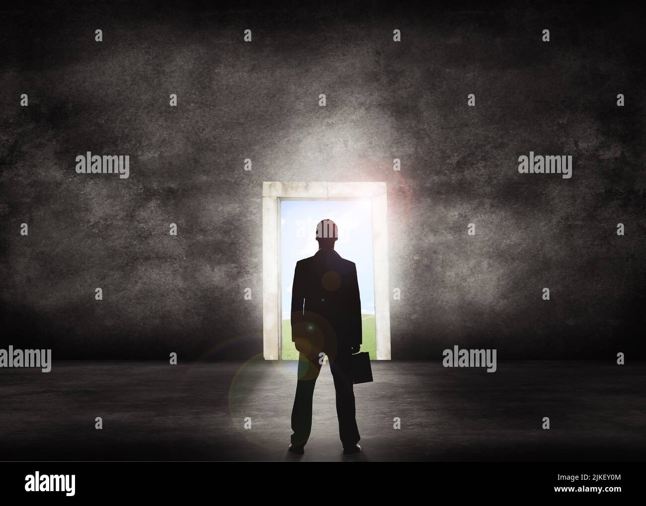 Silhouette eines Geschäftsmannes, der vor einer Lichttür zum Erfolg steht. Business-Profi mit Blick auf eine glänzende Zukunft vor ihm. Isoliert Stockfoto