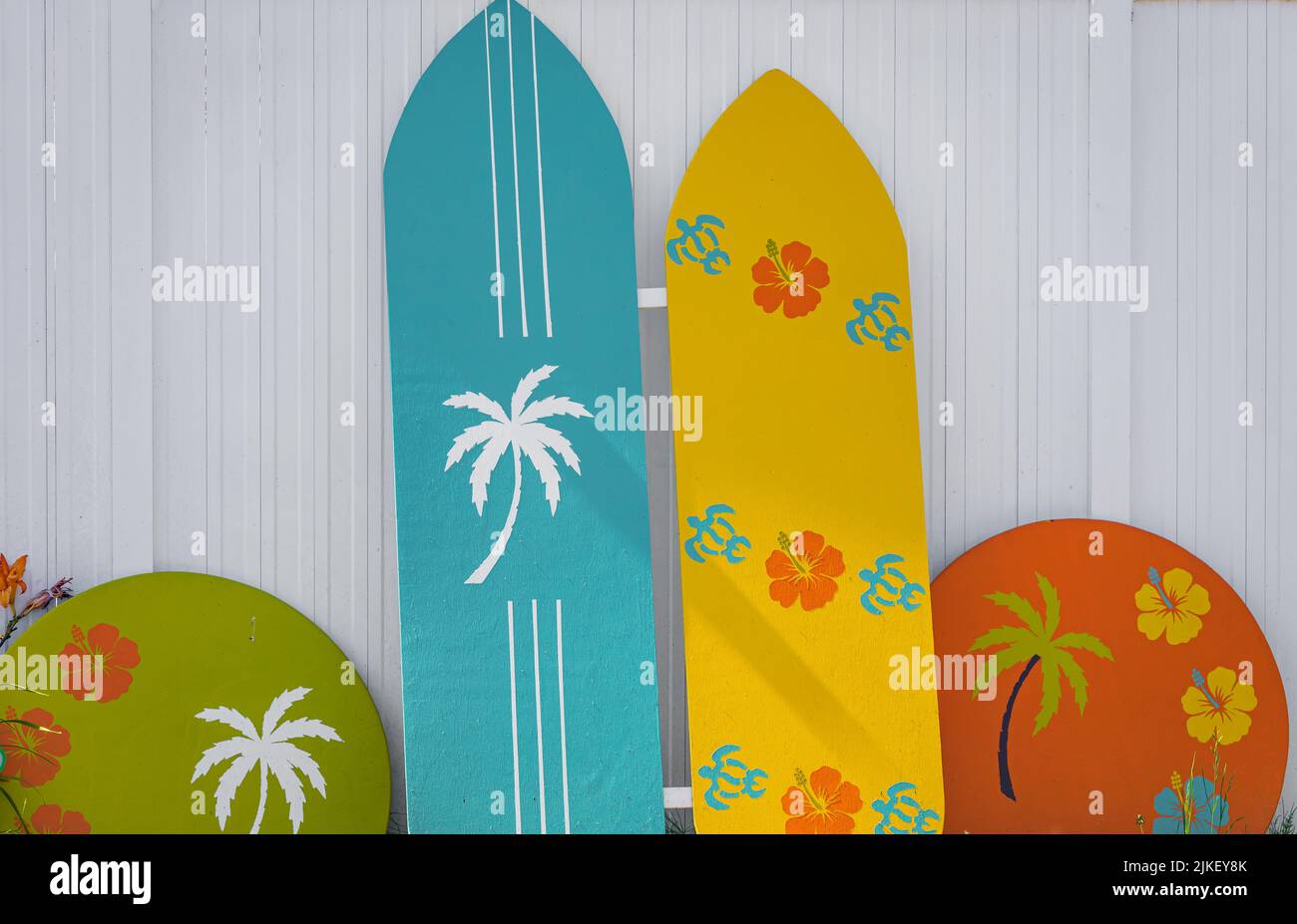 Buntes Surfbrett auf weißem Hintergrund. Farbige Surfbretter, die sich an einen Holzzaun lehnen. Reisefoto, niemand, Platz für Text kopieren Stockfoto