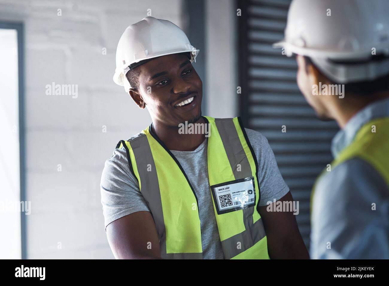 Überlasst es mir. Zwei junge Kontraktoren stehen zusammen im Lager und führen eine Diskussion. Stockfoto