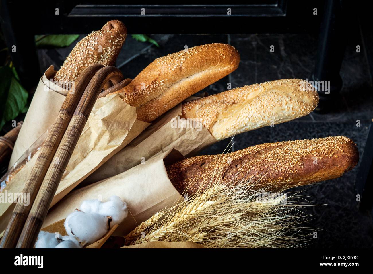 Frisch gebackenes Brot liegt in einem Korbkorb. Mehrere verschiedene frische Brote in Öko-Paket zusammen mit Ähren von Weizen. Stockfoto