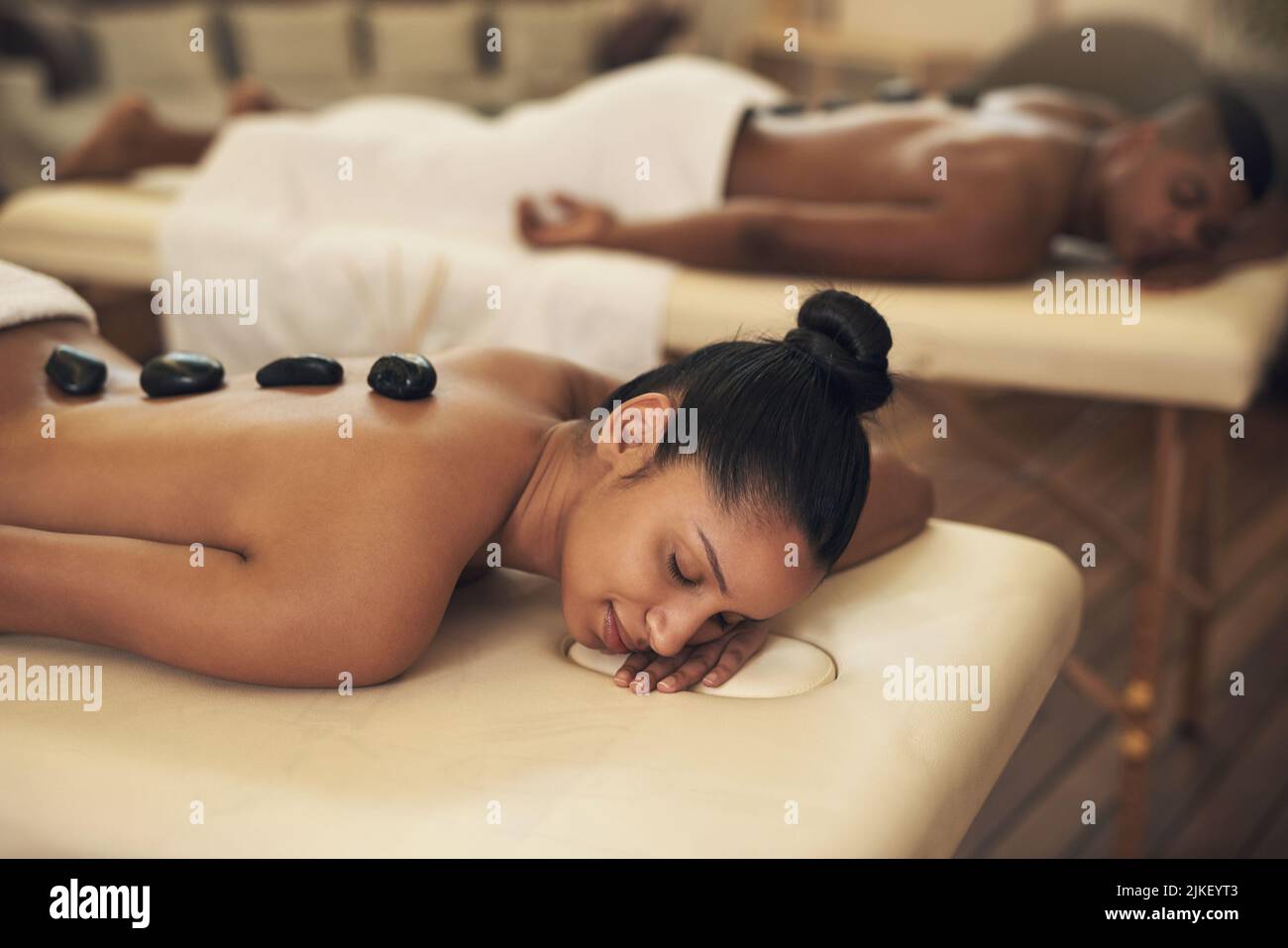 Entspannen Sie sich, während wir die müden Muskeln beruhigen. Eine junge Frau bekommt eine Hot-Stone-Massage in einem Spa. Stockfoto