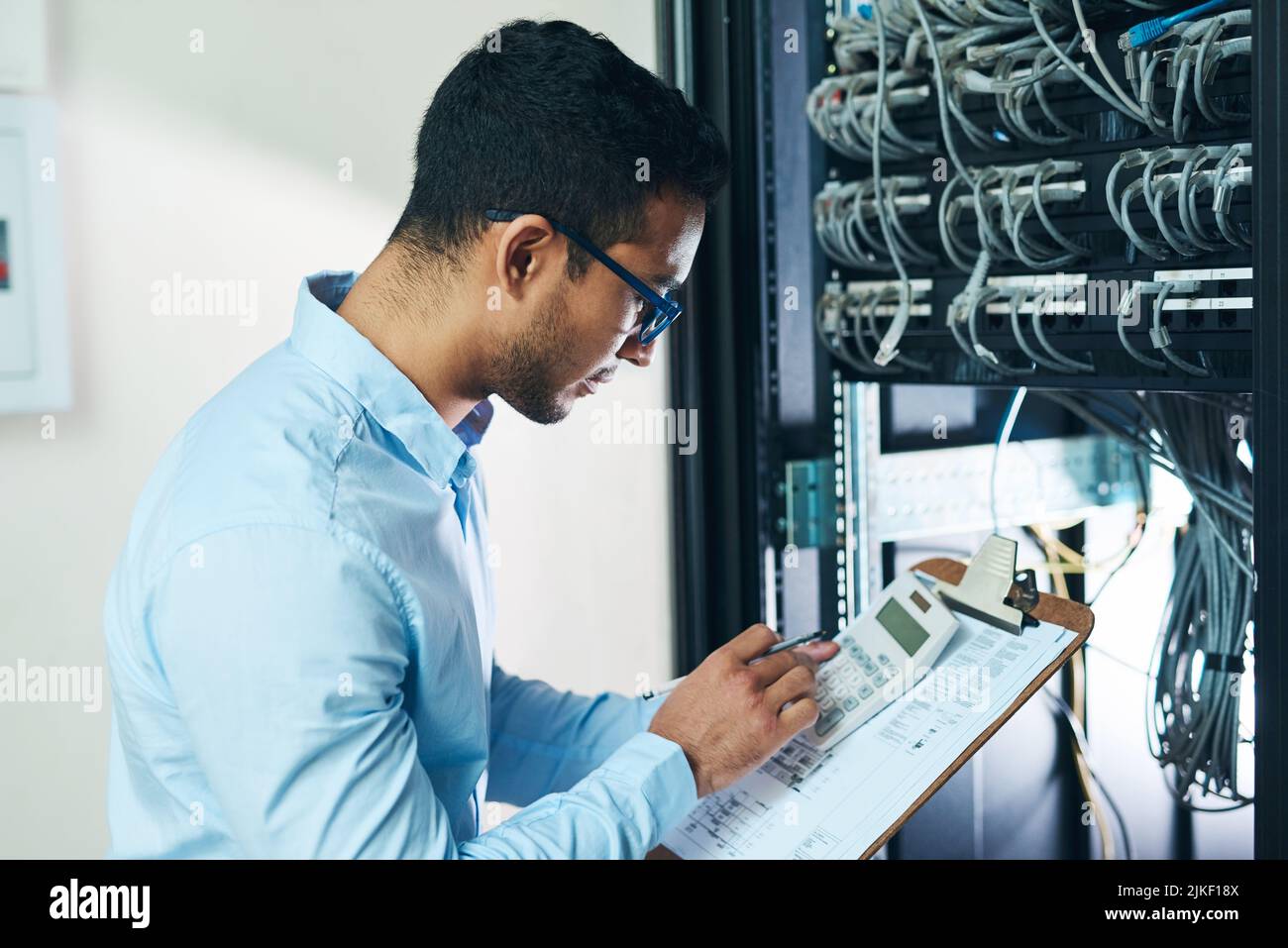 Das summieren sich nicht. Ein hübscher junger Techniker, der alleine steht und auf den Mainframe schaut. Stockfoto
