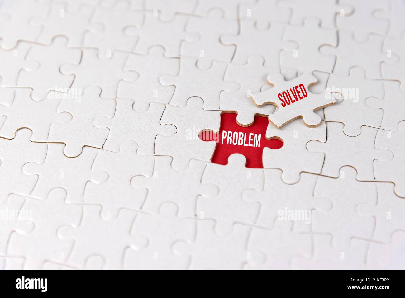 Weißer Puzzle-Hintergrund mit fehlenden Stück auf rot mit Text. Geschäftskonzept. Problem gelöst. Teamarbeit, Führung und Lösung. Stockfoto