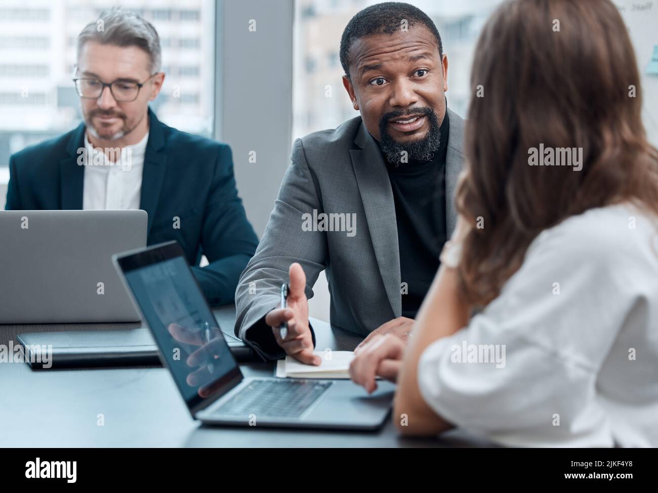 Eine Gruppe von Kollegen aus dem Unternehmensbereich, die sich im Sitzungssaal um den Tisch treffen. Stockfoto