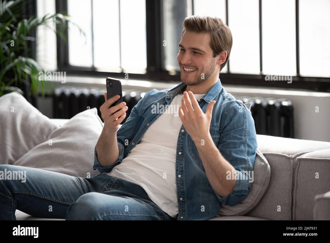 Online-Videoanruf. Positiver Mann winkt der Hand zur Webcam und hat ein angenehmes Gespräch mit Freunden oder der Familie Stockfoto