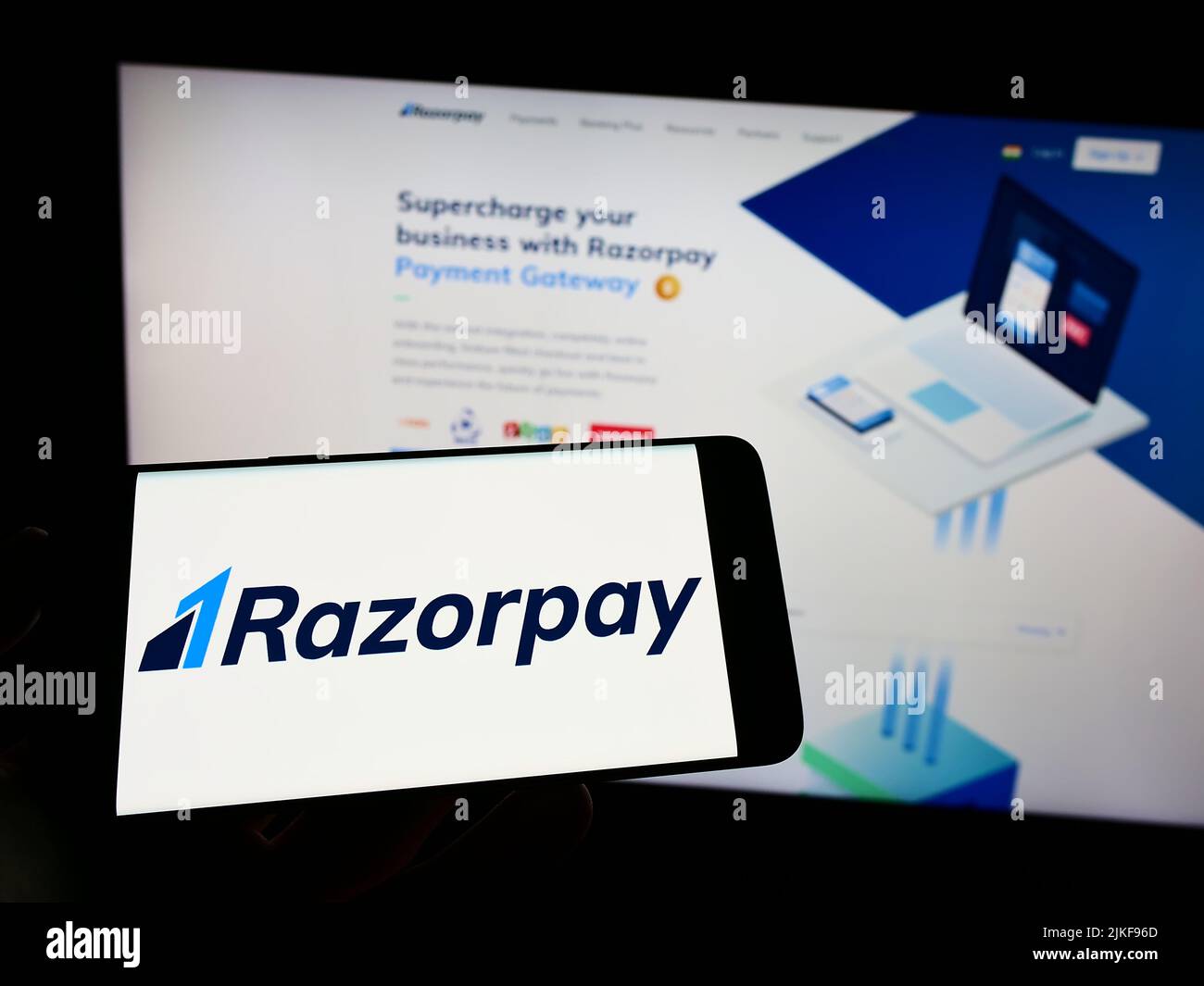 Person, die Mobiltelefon mit Logo der indischen Firma Razorpay Software Private Limited auf dem Bildschirm vor der Webseite hält. Konzentrieren Sie sich auf die Telefonanzeige. Stockfoto