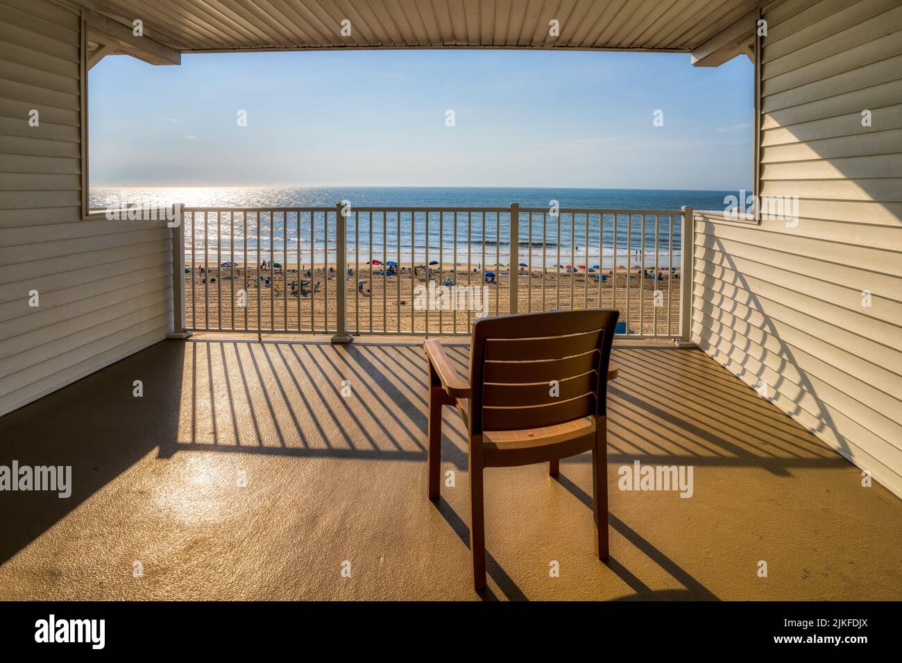 Eine schöne Aufnahme eines Holzstuhls auf einer Veranda gegen das Meer an einem sonnigen Tag Stockfoto