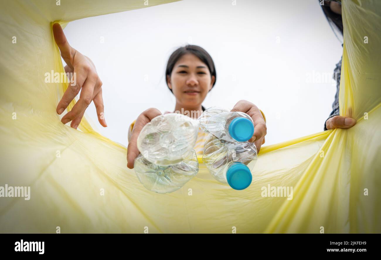 Frau wirft Plastikmüll in einen Müll. Frau, die Müllplastiktüten in den Müll legt Stockfoto