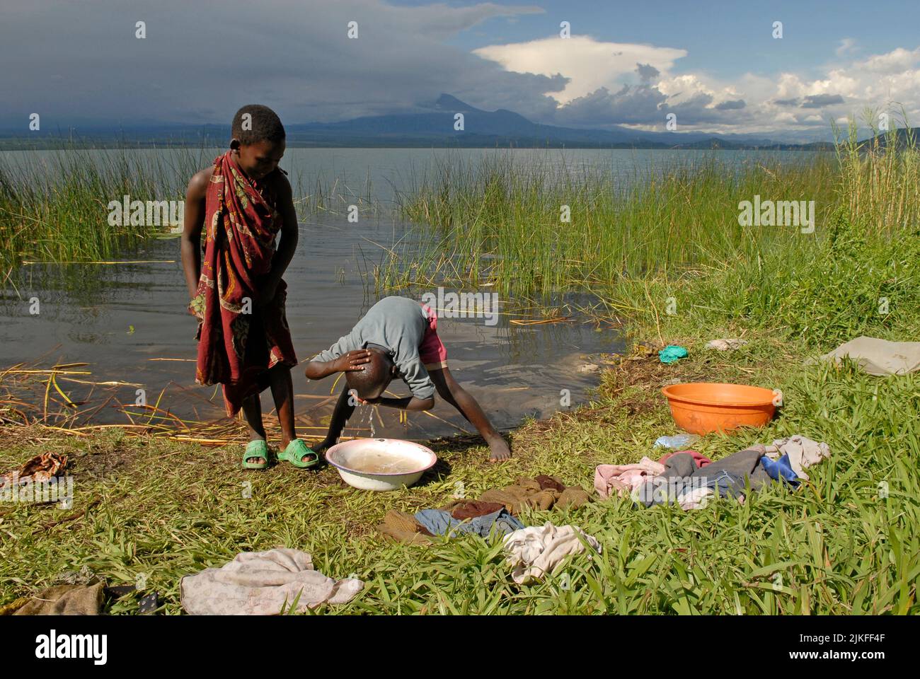 Ein Junge wäscht sich mit Wasser aus dem Eimer am Ufer des Sees Kivu in Nord-Kivu, DR Kongo Afrika Stockfoto