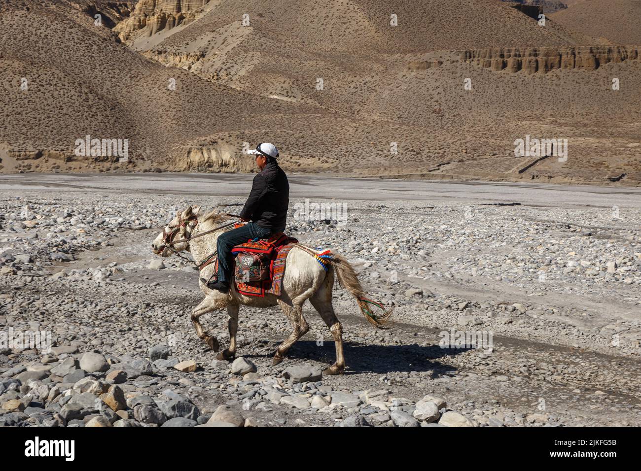 Kagbeni, Mustang District, Nepal - 23. November 2016: Ein nicht identifizierter nepalesischer Mann reitet auf einer Straße im Himalaya entlang des Kali Gandaki Riv Stockfoto