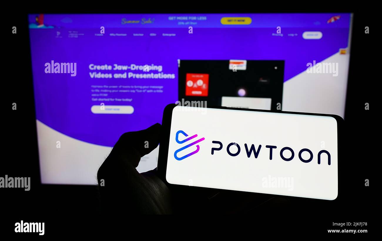 Person, die Mobiltelefon mit dem Logo der Animationssoftware-Firma Powtoon.com Inc. Auf dem Bildschirm vor der Webseite hält. Konzentrieren Sie sich auf die Telefonanzeige. Stockfoto