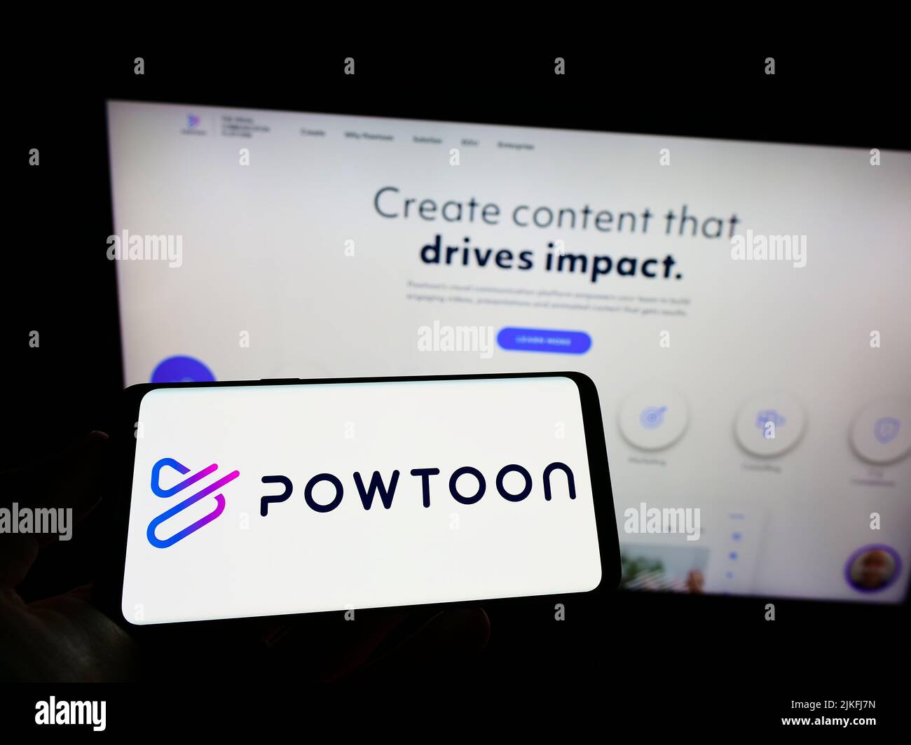Person, die Mobiltelefon mit Logo der britischen Animationssoftware Powtoon.com Inc. Auf dem Bildschirm vor der Webseite hält. Konzentrieren Sie sich auf die Telefonanzeige. Stockfoto